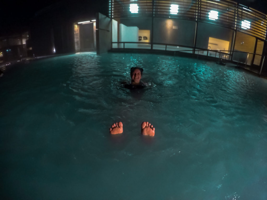 Photo at night in the Blue Lagoon showing Tabitha and her feet floating in the water. Emphasis on the Liberation of Standing Naked In a Women's Locker Room